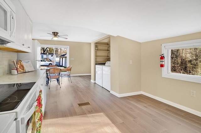 kitchen featuring white appliances, white cabinets, ceiling fan, light hardwood / wood-style floors, and washing machine and clothes dryer