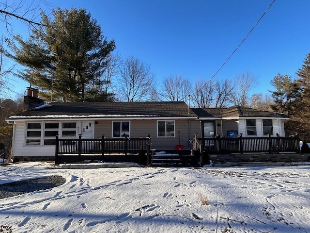 snow covered rear of property featuring a deck