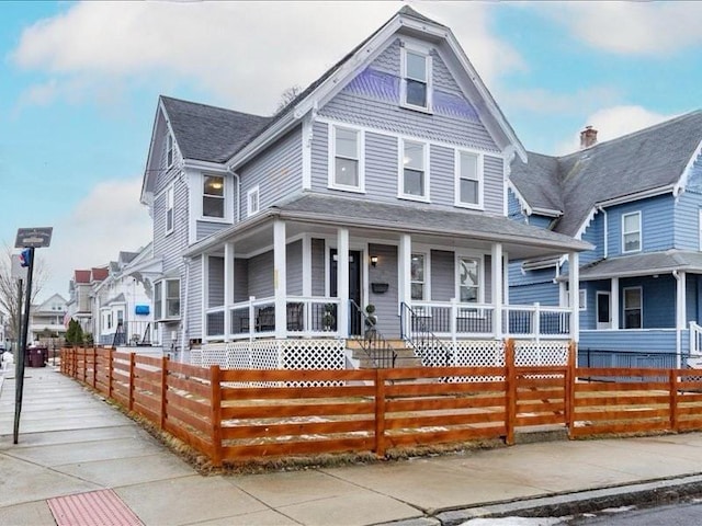 victorian-style house featuring a fenced front yard and a porch