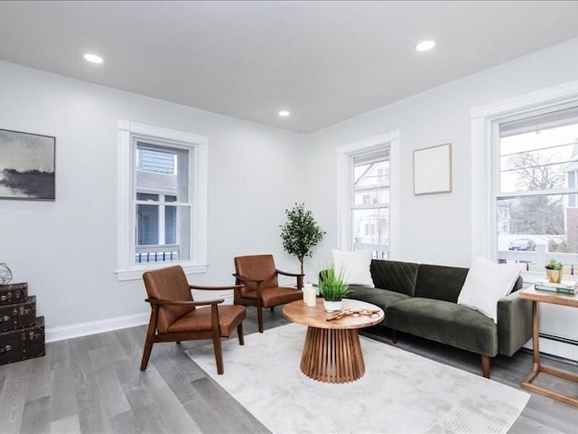 sitting room with baseboards, plenty of natural light, wood finished floors, and recessed lighting