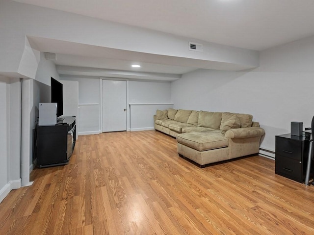 living room with visible vents, baseboards, a baseboard heating unit, and light wood-type flooring