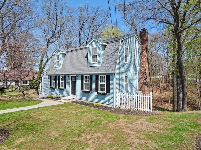 colonial inspired home with a front lawn, fence, a gambrel roof, roof with shingles, and a chimney