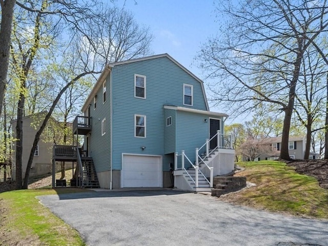 view of front facade with an attached garage, driveway, and stairs