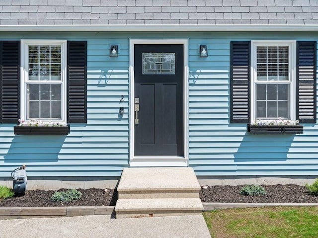 view of exterior entry with a shingled roof