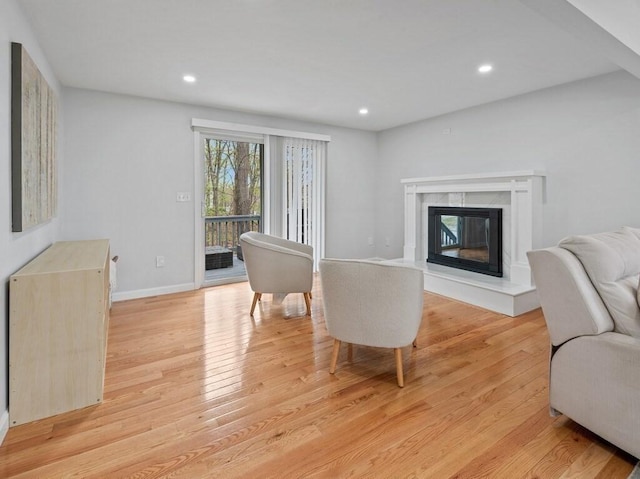 living room featuring light wood-type flooring, recessed lighting, baseboards, and a high end fireplace