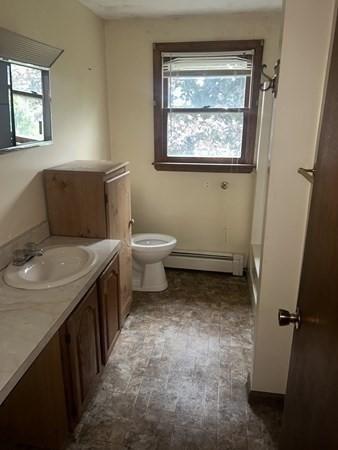 bathroom with vanity, a baseboard heating unit, and toilet