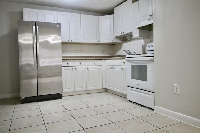 kitchen featuring white electric range oven, decorative backsplash, freestanding refrigerator, white cabinets, and under cabinet range hood