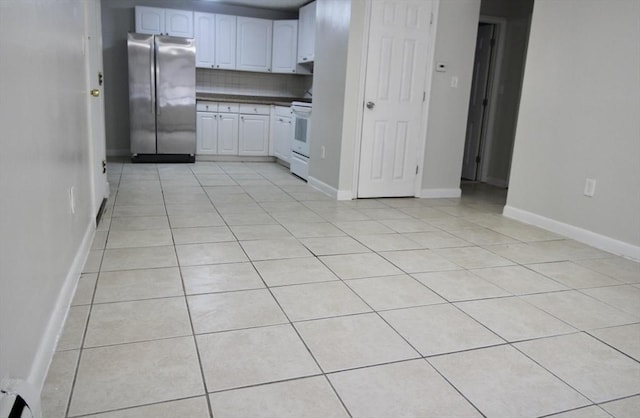 kitchen featuring light tile patterned floors, decorative backsplash, electric stove, dark countertops, and freestanding refrigerator