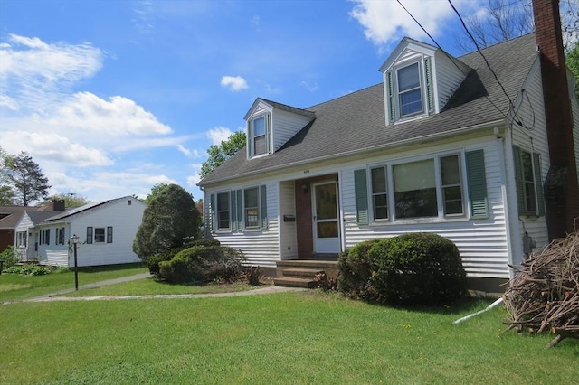 new england style home featuring a front lawn, a chimney, and roof with shingles