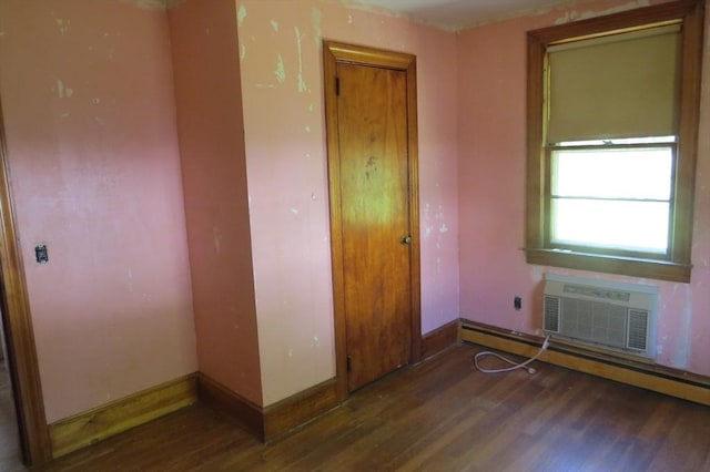 unfurnished room with wood finished floors, a wall unit AC, baseboard heating, and baseboards