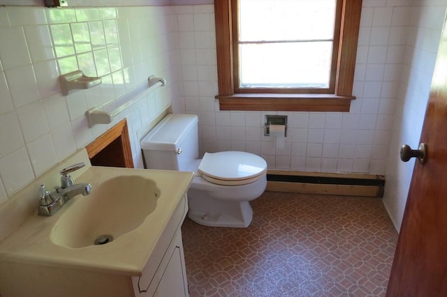 half bath with tile walls, a baseboard radiator, toilet, and vanity