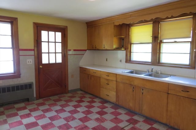 kitchen with radiator, a sink, light floors, light countertops, and healthy amount of natural light