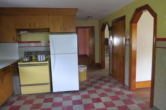 kitchen featuring white appliances, arched walkways, light flooring, and light countertops
