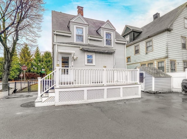 10 Windom St, Boston, MA 02134 - view of front of house featuring a chimney, a storage unit, fence, and an outdoor structure