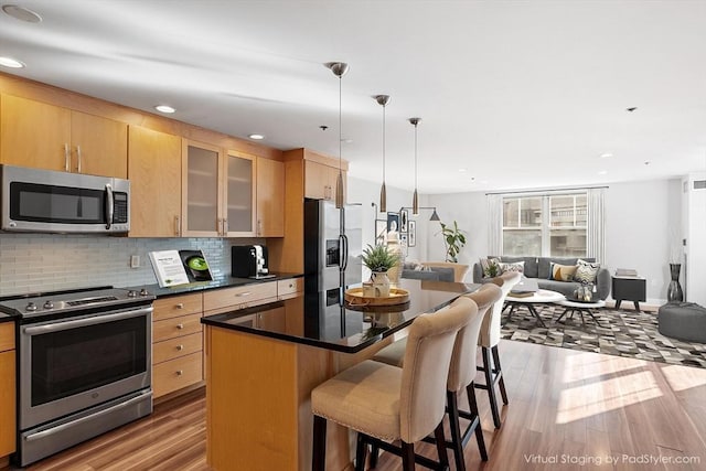 kitchen with a breakfast bar, a center island, hanging light fixtures, stainless steel appliances, and backsplash