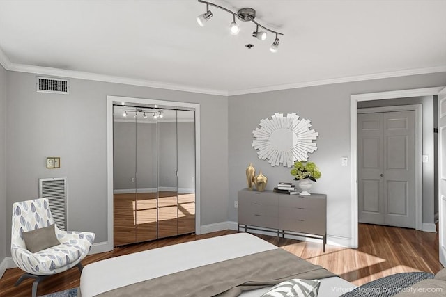 bedroom with crown molding, hardwood / wood-style floors, track lighting, and a closet