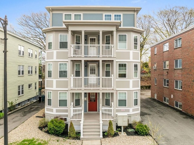 view of front of house with stucco siding, a balcony, and covered porch