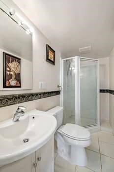 bathroom with toilet, tile patterned flooring, an enclosed shower, and vanity