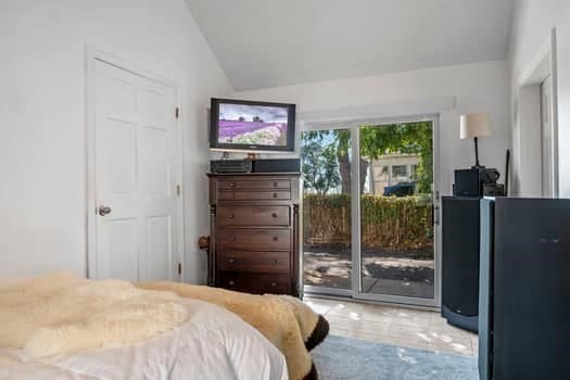 tiled bedroom featuring lofted ceiling and access to exterior