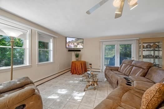 tiled living room featuring ceiling fan and a baseboard radiator