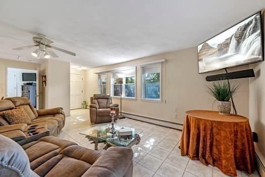 tiled living room featuring ceiling fan and baseboard heating