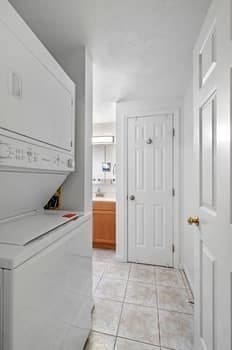 laundry room with stacked washer and clothes dryer and light tile patterned flooring