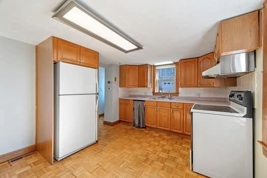 kitchen with tasteful backsplash, extractor fan, white appliances, and light parquet floors