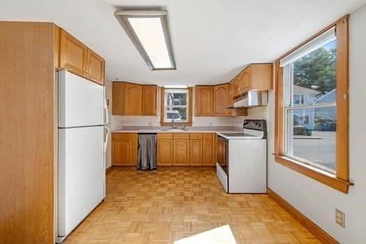 kitchen with sink, ventilation hood, white appliances, and light parquet flooring