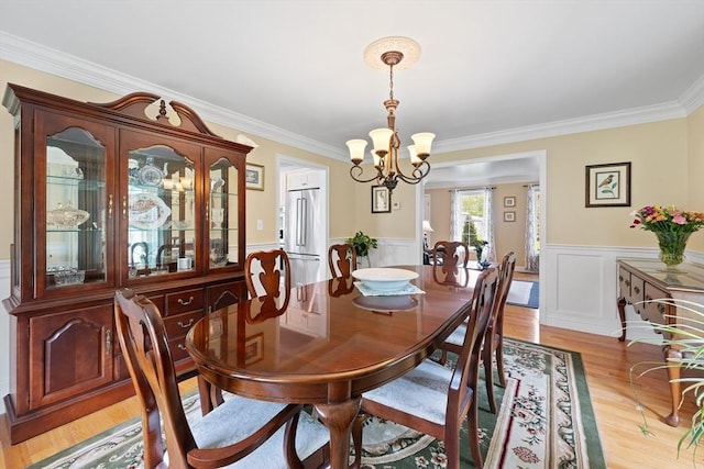 172 Orchard St, Newbury, MA 01922 - dining area with a chandelier, crown molding, light wood-style floors, and a wainscoted wall