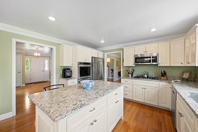 172 Orchard St, Newbury, MA 01922 - kitchen featuring appliances with stainless steel finishes, crown molding, a center island, light stone counters, and light wood-type flooring