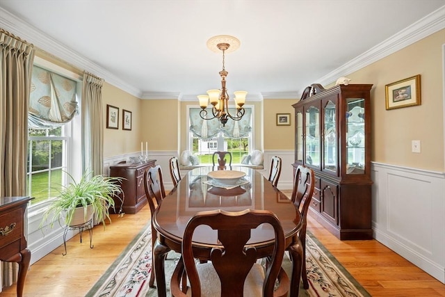 172 Orchard St, Newbury, MA 01922 - dining area with a chandelier, a wainscoted wall, light wood-type flooring, crown molding, and a decorative wall