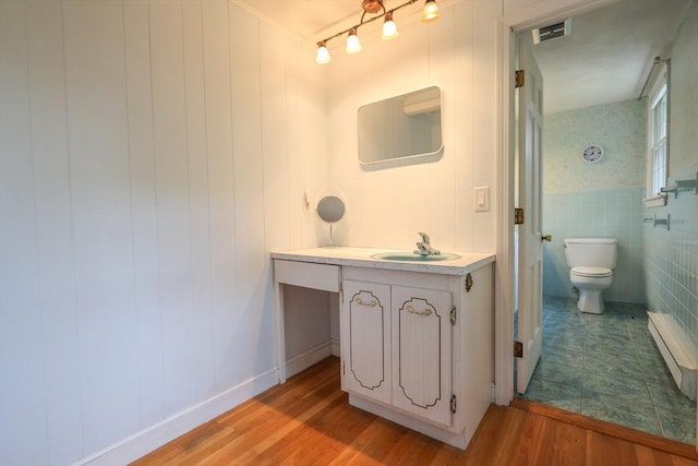 10 Emile Cir, Medford, MA 02155 - bathroom with baseboard heating, wood finished floors, vanity, toilet, and tile walls