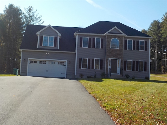 colonial inspired home featuring a garage and a front lawn