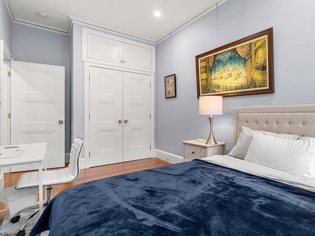 bedroom featuring wood-type flooring, crown molding, and a closet