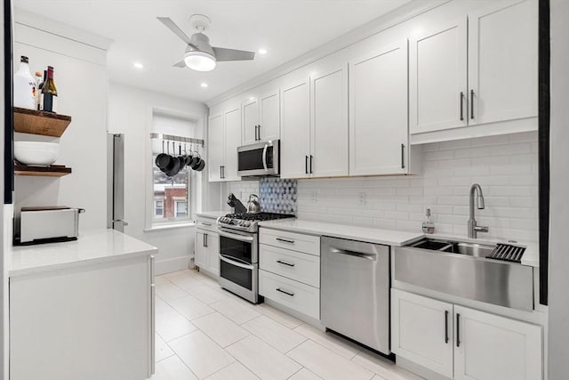 kitchen with sink, ceiling fan, decorative backsplash, appliances with stainless steel finishes, and white cabinetry