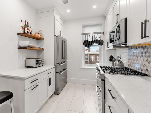 kitchen featuring white cabinetry, backsplash, light stone countertops, and stainless steel appliances