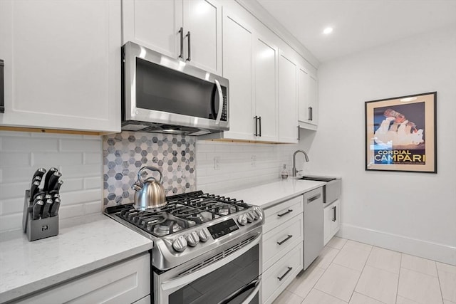 kitchen featuring light stone countertops, sink, white cabinets, and stainless steel appliances