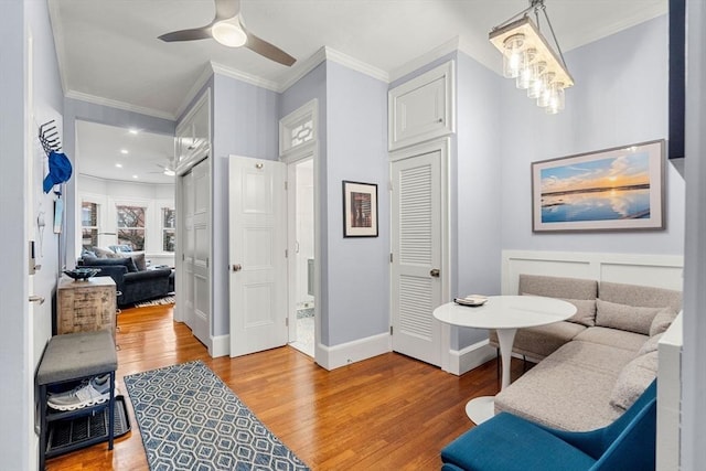 living area with hardwood / wood-style floors, ceiling fan, and crown molding