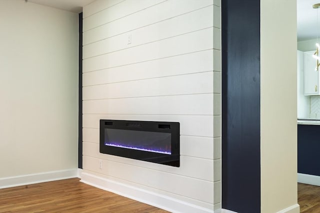 details featuring a fireplace, baseboards, and wood finished floors