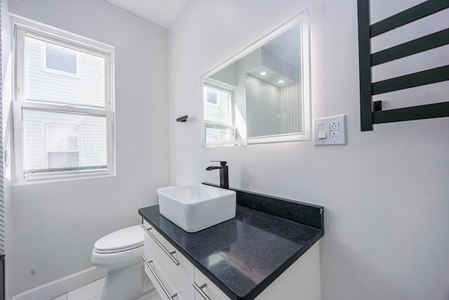 bathroom with vanity, toilet, a shower, and baseboards