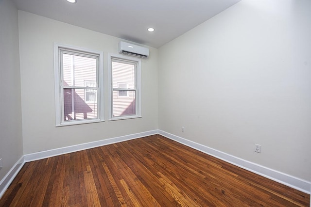 spare room featuring a wall mounted air conditioner, baseboards, recessed lighting, and dark wood-style flooring