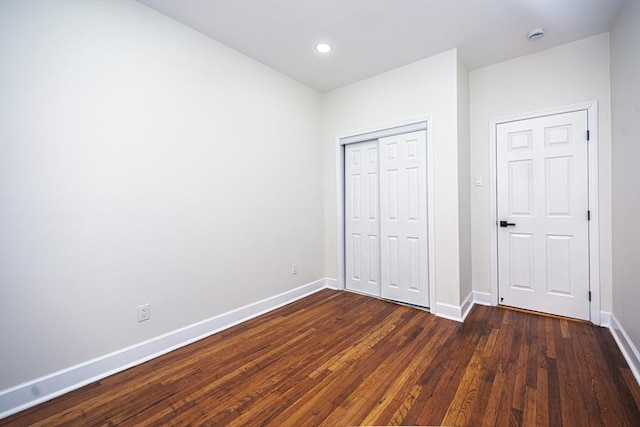 unfurnished bedroom with dark wood-type flooring, recessed lighting, baseboards, and a closet