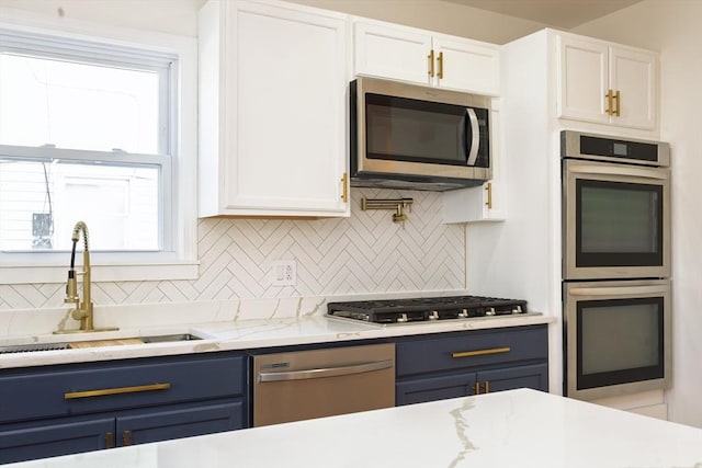 kitchen featuring blue cabinetry, a healthy amount of sunlight, appliances with stainless steel finishes, and a sink