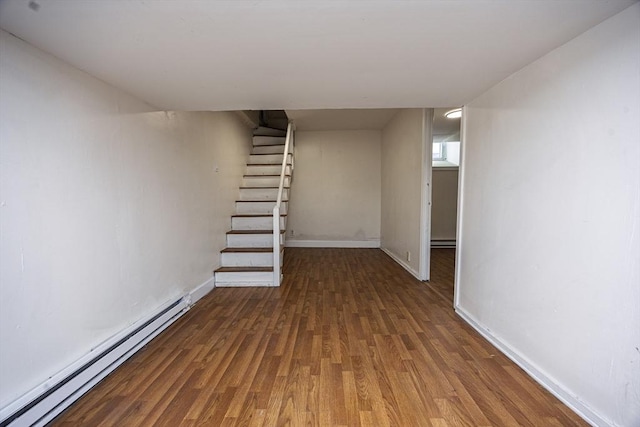 finished basement with stairway, baseboards, baseboard heating, and wood finished floors