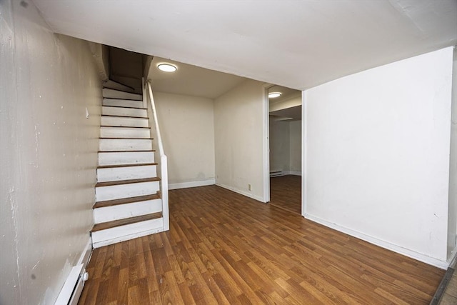 below grade area with stairs, wood finished floors, baseboards, and a baseboard heating unit