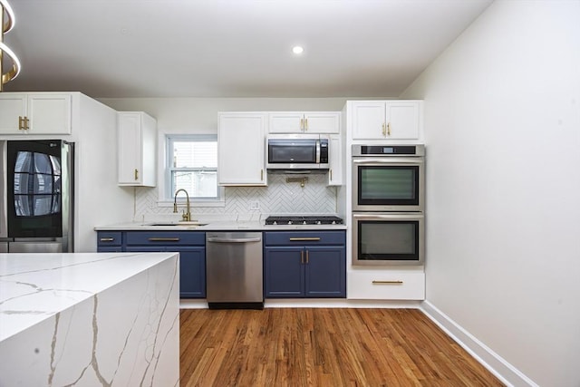 kitchen featuring a sink, blue cabinets, appliances with stainless steel finishes, and white cabinetry