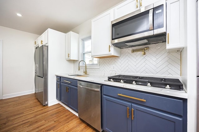 kitchen featuring appliances with stainless steel finishes, white cabinetry, blue cabinets, and a sink