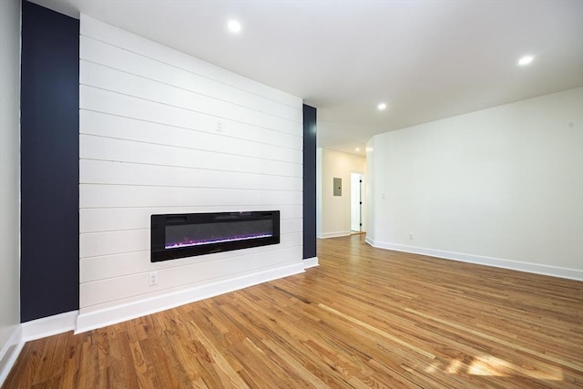 unfurnished living room featuring recessed lighting, baseboards, light wood finished floors, and a large fireplace