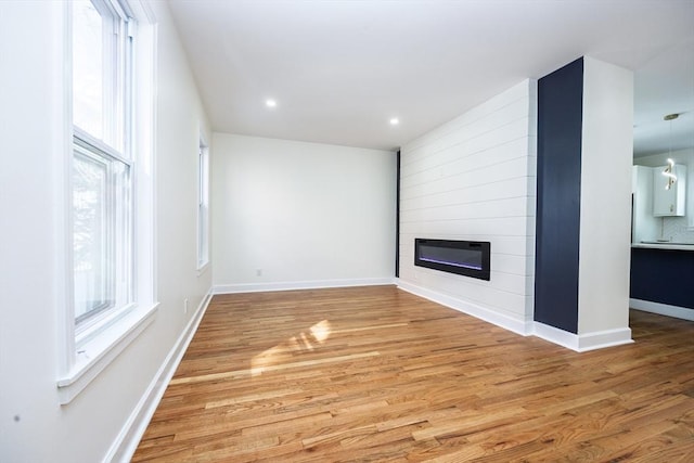 unfurnished living room with recessed lighting, a fireplace, light wood-style floors, and baseboards