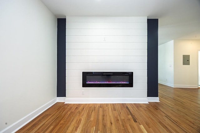 interior details with electric panel, wood finished floors, baseboards, and a large fireplace